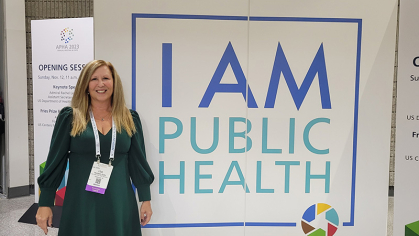Lisa Gulla standing in front of sign that says I am Public Health