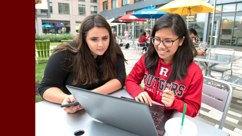 Rutgers students working on a laptop outdoors