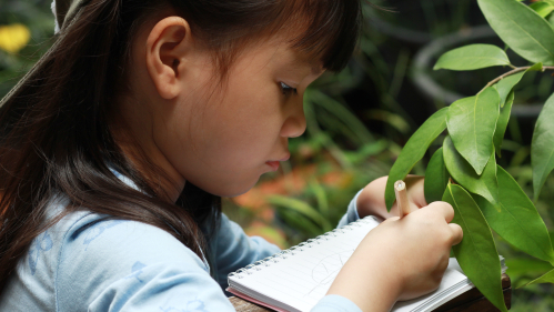 girl in front of plant taking notes