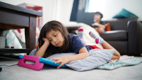 little girl laying on floor looking frutrated at her book