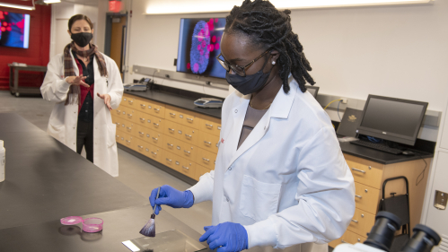 Original Caption: (l. t. r.) From a safe distance Kimberlee Sue Moran, Associate Teaching Professor and Director of Forensics, Department of Chemistry observes Sherifat Alaka (CAS '22) dust for fingerprints during special on-location work in the forensic