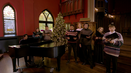 Members of the Rutgers Kirkpatrick Choir and Rutgers University Glee Club singing in front of a piano