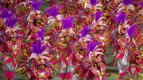 A group of samba dancers in bright red and purple costumes in Sao Paolo, Brazil, during Carival in February 2020