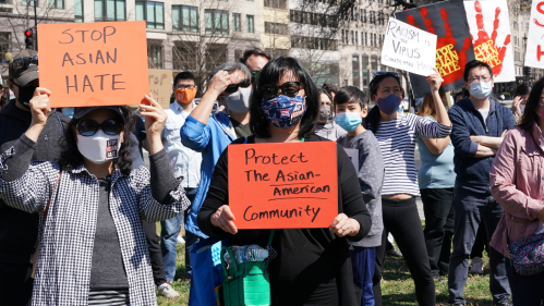 protesters holding signs of support for the Asiam American community