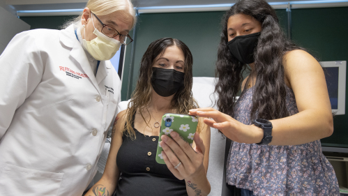 Gloria Bachmann, from left, of the RWJMS Women's Health Institute, expectant mother Michelle Leighton, and student Zoe Reich (SAS ’24) review the Mother's Touch app, a project launched by Reich.