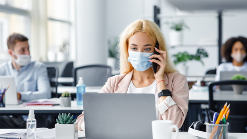 Woman working in office with mask on.