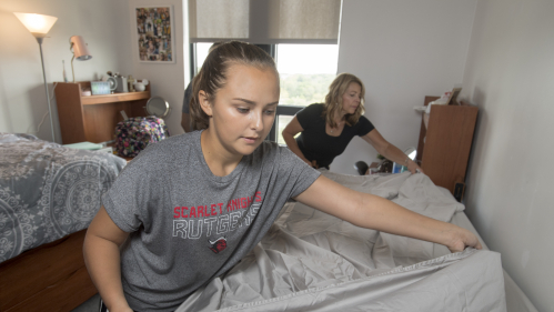 a student and her mother making her bed