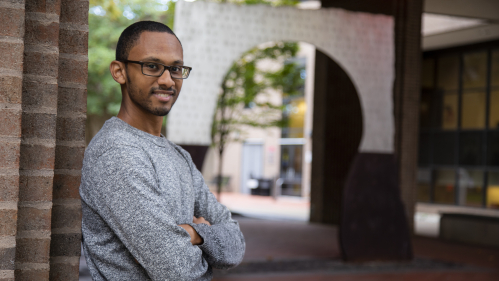 student standing against a brick wall on the Camden campus