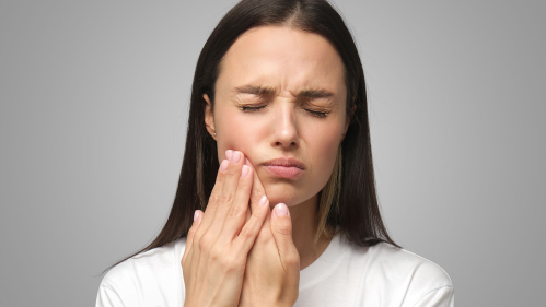 Woman with toothache rubs cheek
