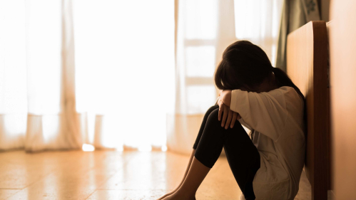 sad woman sits against wall