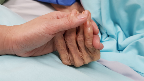 woman grasps dying patient's hand