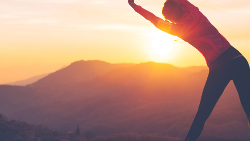 person stretching in front of a sunrise