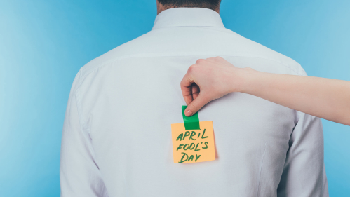 person putting April Fool's Day note on someone's back