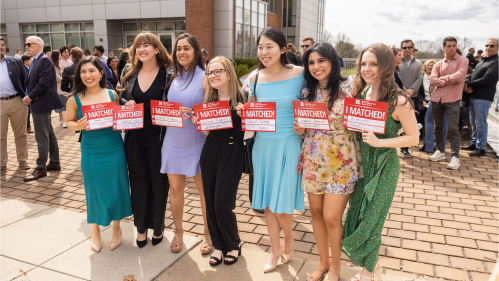 Women Med Students holding up signs that say where they matched 