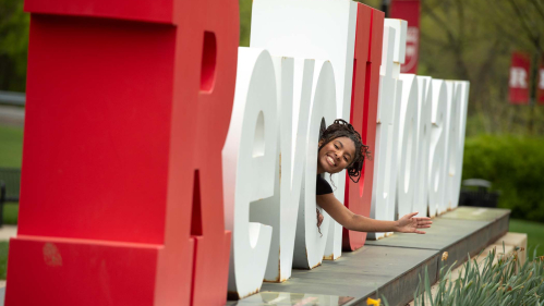 Camryn Harrell waves from inside one of the letters at the Revolutionary monument on Busch campus