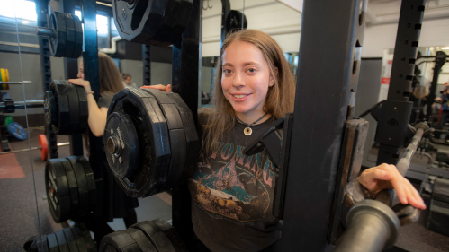 Naomi Kutin surrounded by weightlifiting equipment at Rutgers