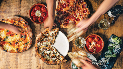 Hands reaching for slices of pizza