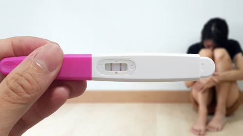 Positive pregnancy test with sad woman.
