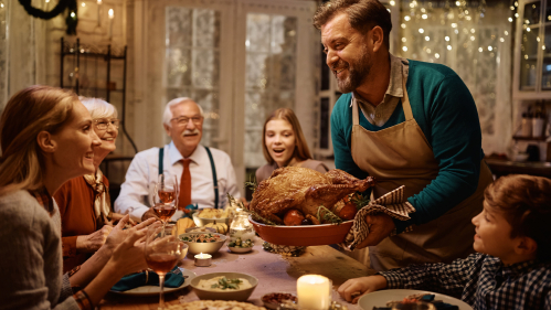 man holding thanksgiving turkey at the dinner table
