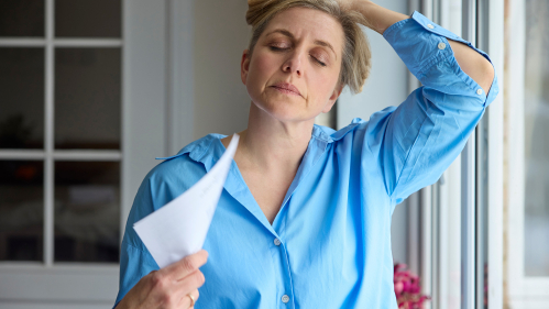 Menopausal woman fanning her self during a hot flash.
