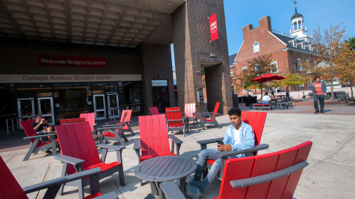 Mann Sharma (SOE ’25) sitting on the new patio furniture in front of the College Ave Student Center. 