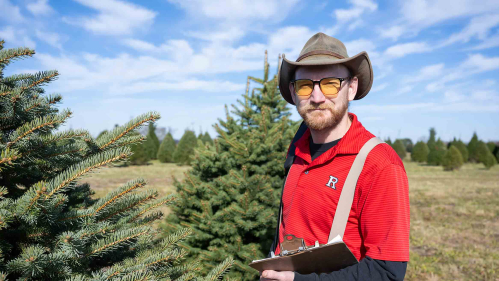 Rutgers scientist Timothy Waller stands in a field of Christmas trees.