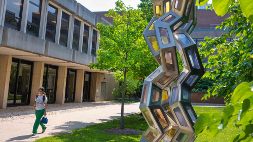 A student walks by the sculpture “Synergy” outside of the Proteomics Building on Busch campus at Rutgers-New Brunswick.