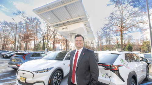 William O’Brien, assistant vice president of IP&O with two of the 24 new electric vehicles purchased this fall as part of a decadelong plan to phase out all 700 of Rutgers' gas-powered vehicles. Rutgers also purchased its first two solar-powered Beam ARC charging stations this fall. This one is located at 33 Knightsbridge in Piscataway.