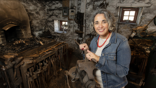 Douglass alumna Gina Sampaio in the working black smith shop original to the Red Mill Museum Village.