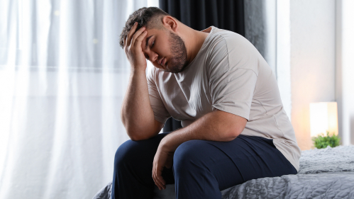 Man sitting on couch holding his head