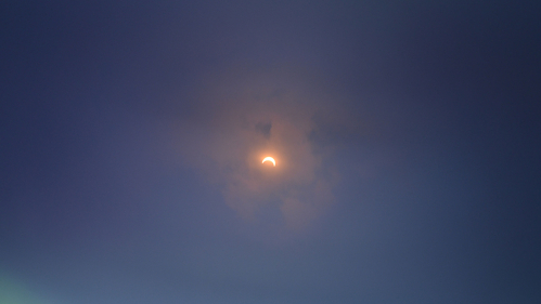 sun partially obscured by the moon at the center of a dark blue sky