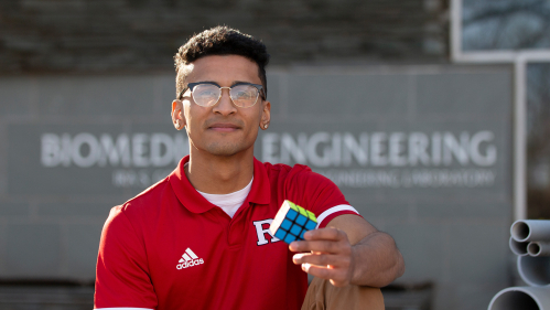 Dylan Sadiq (SOE '22) sits outside the biomedical engineering building holding a Rubik's Cube. 