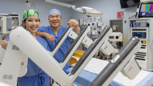 surgeons pose with surgical robot
