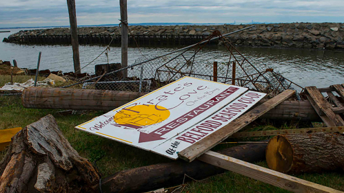 a broken dock and a sign on the ground show the remnants of Super Storm Sandy