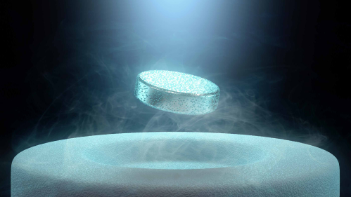silver wafer floats over frozen surface with condensation around it and against a black background