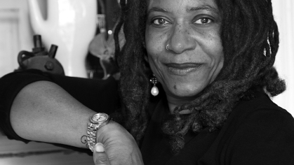 black and white photo portrait of a Black woman leaning on a ledge with a hand sculpture