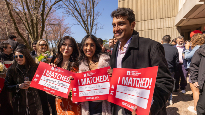 Robert Wood Johnson medical school students hold up signs identifying where they matched