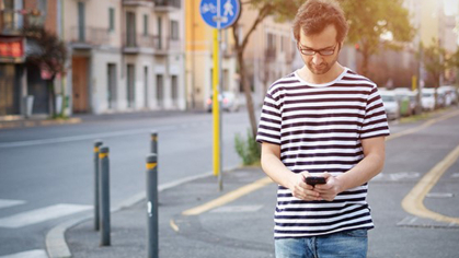 A man walking down the street looking at his cellphone