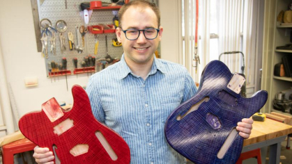 Rutgers student Daniel Hayden holding two guitars of his own design