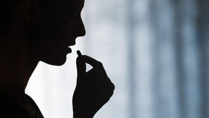A silhouette of someone taking a pill