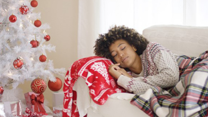Person sleeping on a couch next to a Christmas tree