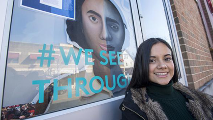 Student stands in front of window artwork 