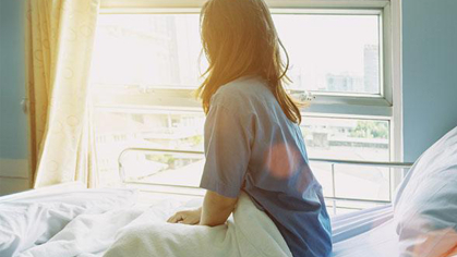 Woman sitting up in hospital bed looking out of the window