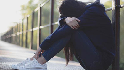 Girl sitting on the ground with her head in her arms