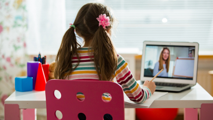 Child watches teacher on computer.