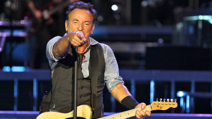 Bruce Springsteen with guitar on stage.
