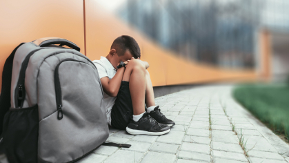 Boy depressed near bookbag