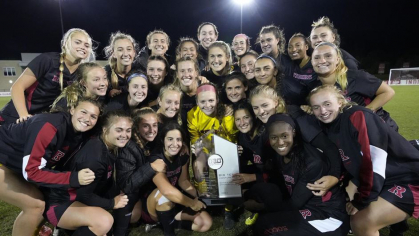 women's soccer team after championship win holding trophy