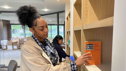 Jassadi Moore (left), a Rutgers graduate student, and undergraduate Stephanie Lopez-Perez (right) add books from Cheryl A. Wall’s collection to the shelves of the new reading room at the Paul Robeson Cultural Center.