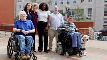Group of Rutgers faculty, some in wheelchairs, some standing, with a service dog